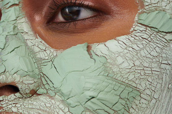 a person with a green facial mask applied